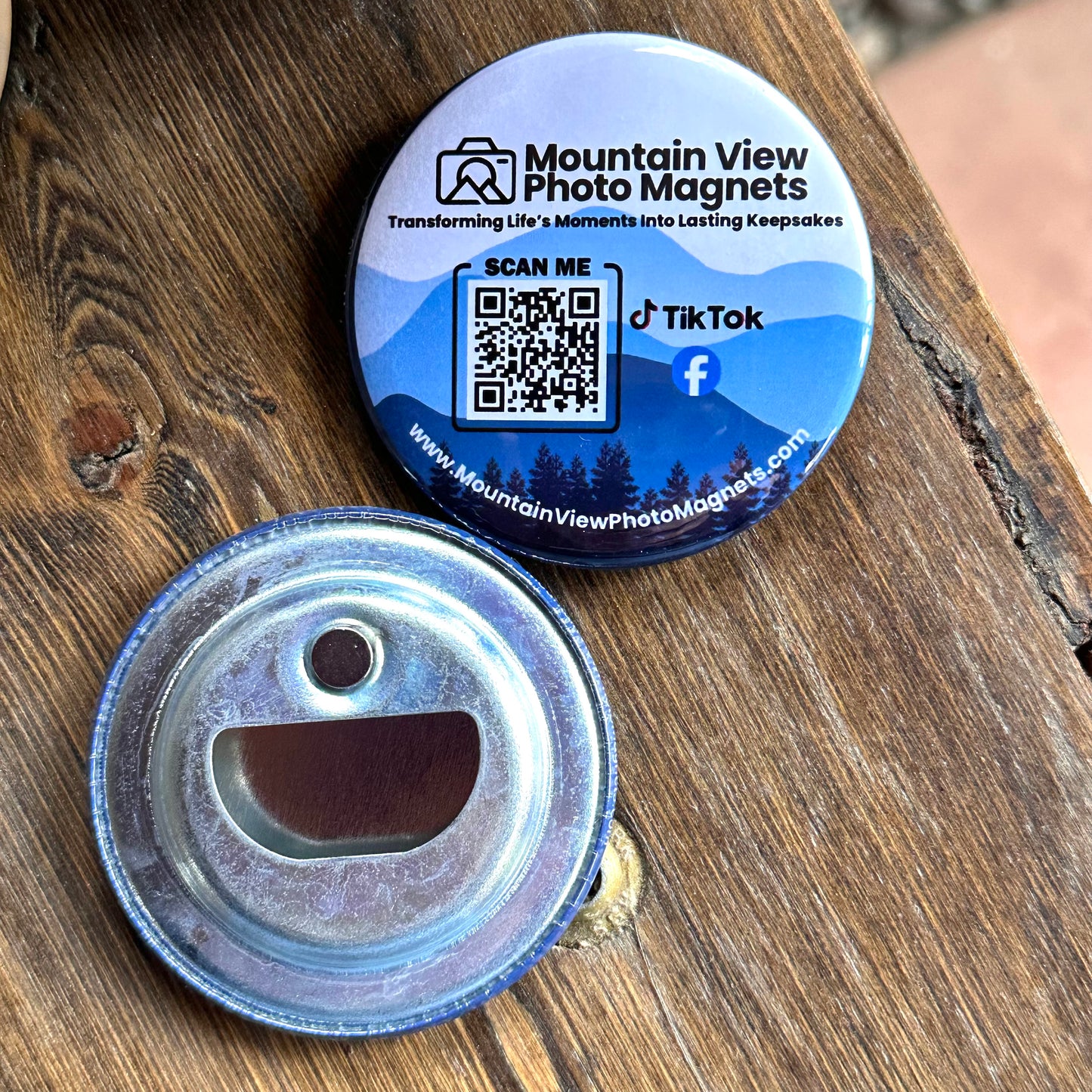 Round metal bottle opener with QR code and branding on a wooden surface