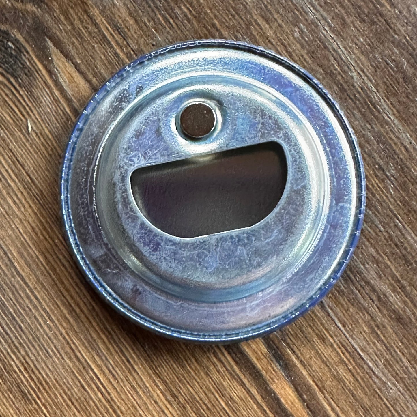 Metal bottle cap opener with magnet reverse side on a wooden surface