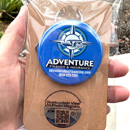 Custom Round 2.25" Bottle Cap Opener blue with Adventure Finance & Insurance logo held in a hand against a natural background in retail packaging.