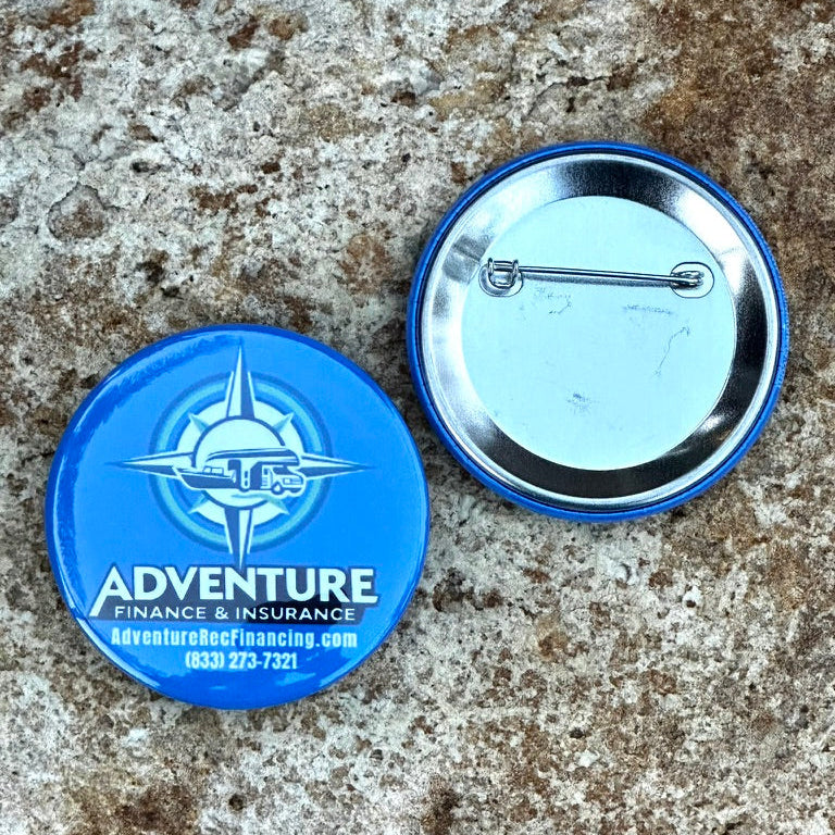 Two buttons, one blue with Adventure Finance & Insurance logo and text, the other clear with a metallic rim, on a textured surface.